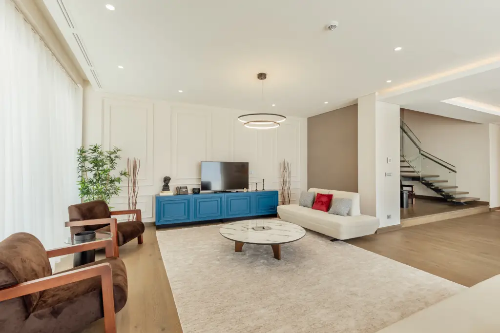 Modern living room with blue TV console, white sofa, and staircase