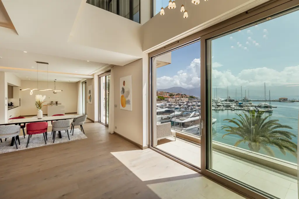 Open-plan dining room with marina view through glass doors