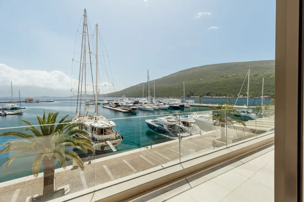Marina with yachts viewed from a balcony with glass railing