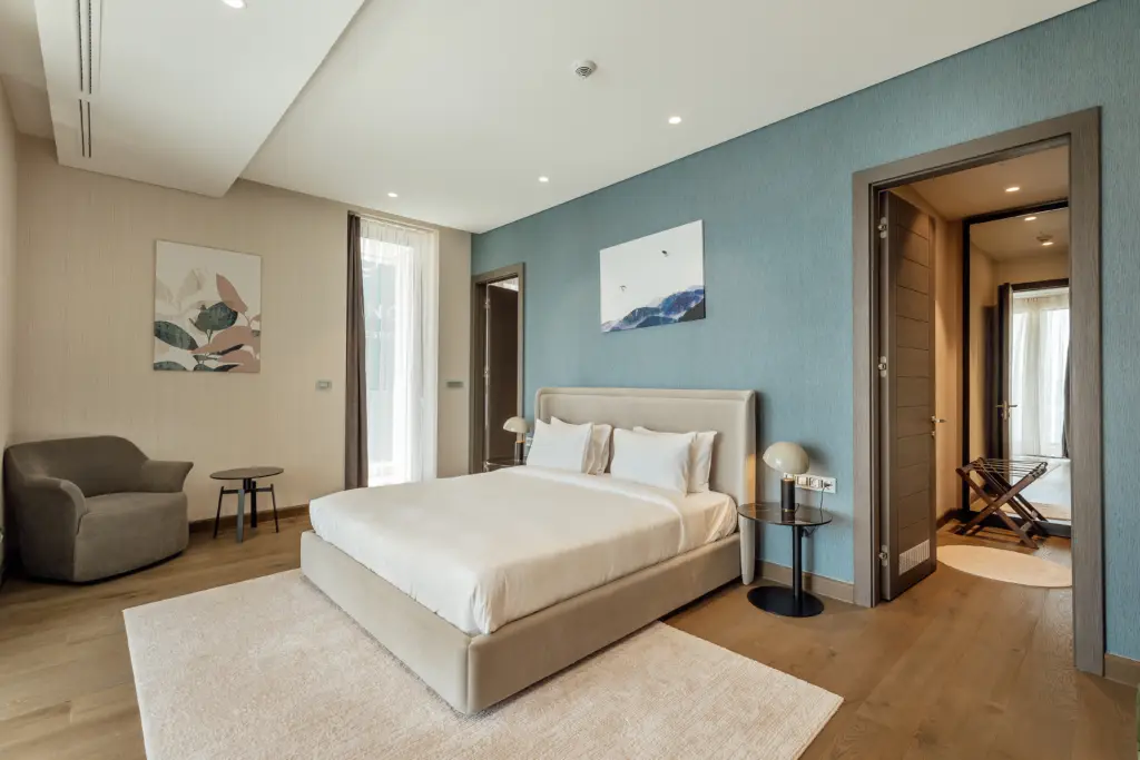 Modern bedroom with bed, armchair, and blue accent wall