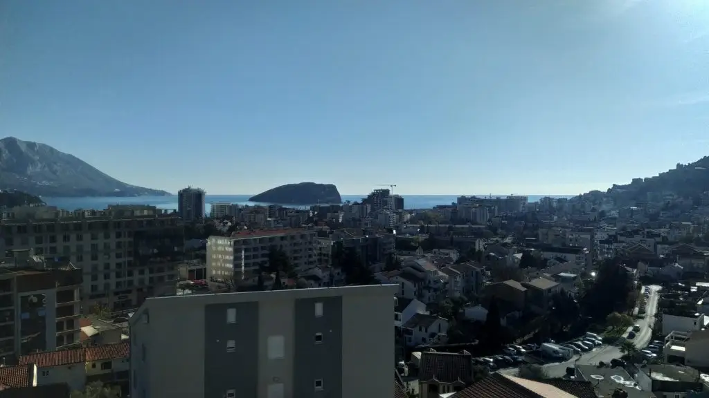 City view with sea and distant mountains under blue sky