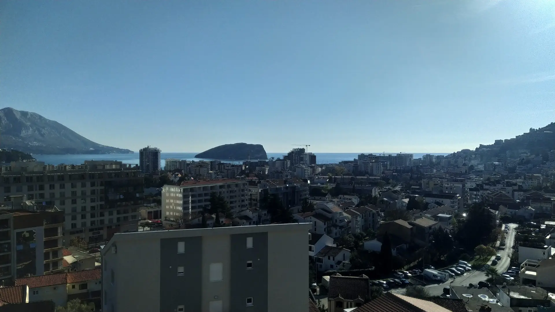 City view with sea and distant mountains under blue sky