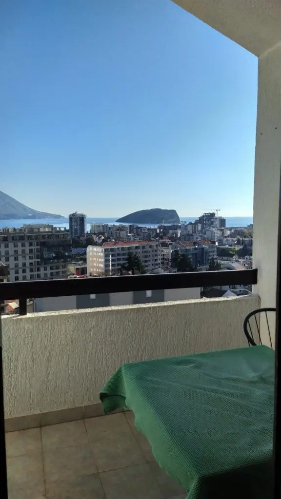 Balcony with green-covered table overlooking city and sea