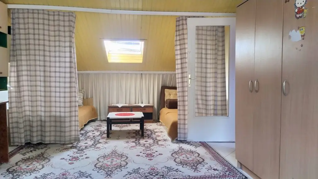 Small attic bedroom with two beds, wardrobe, and patterned rug