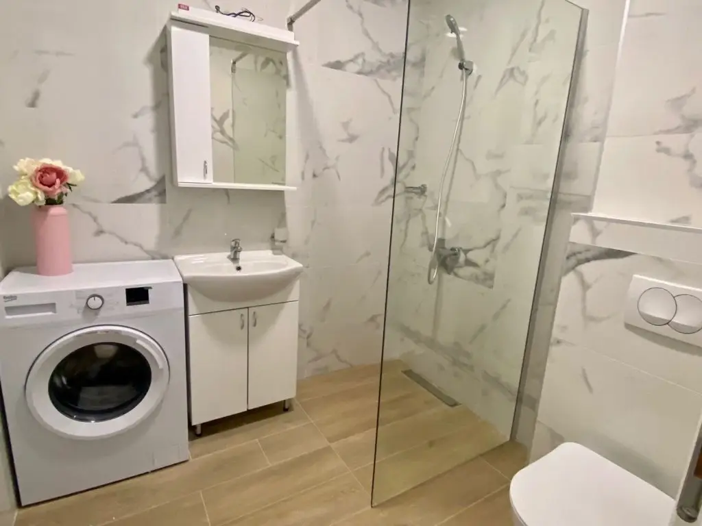 Bathroom with washing machine, sink cabinet, shower, and toilet