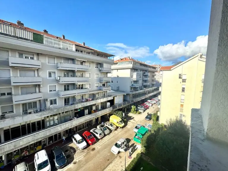 View of apartment buildings and parked cars on a sunny street