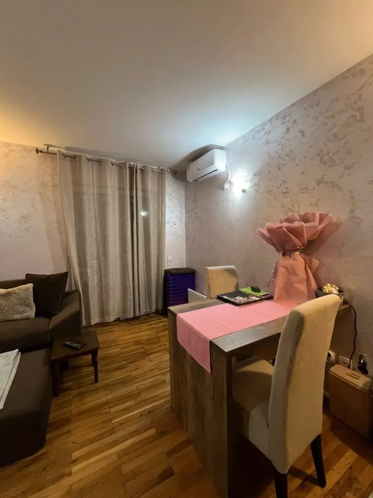 Living room with dining table, sofa, curtains, and wall-mounted air conditioner