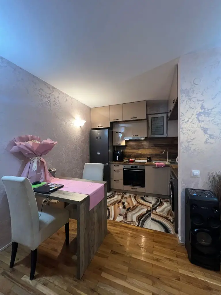 Compact kitchen and dining area with pink tablecloth and chairs