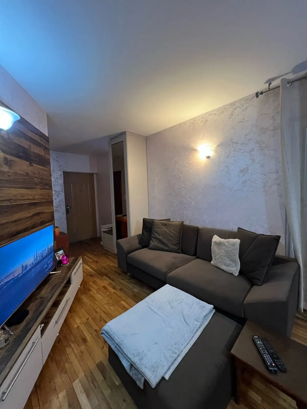 Cozy living room with gray sofa, TV, and wood floor