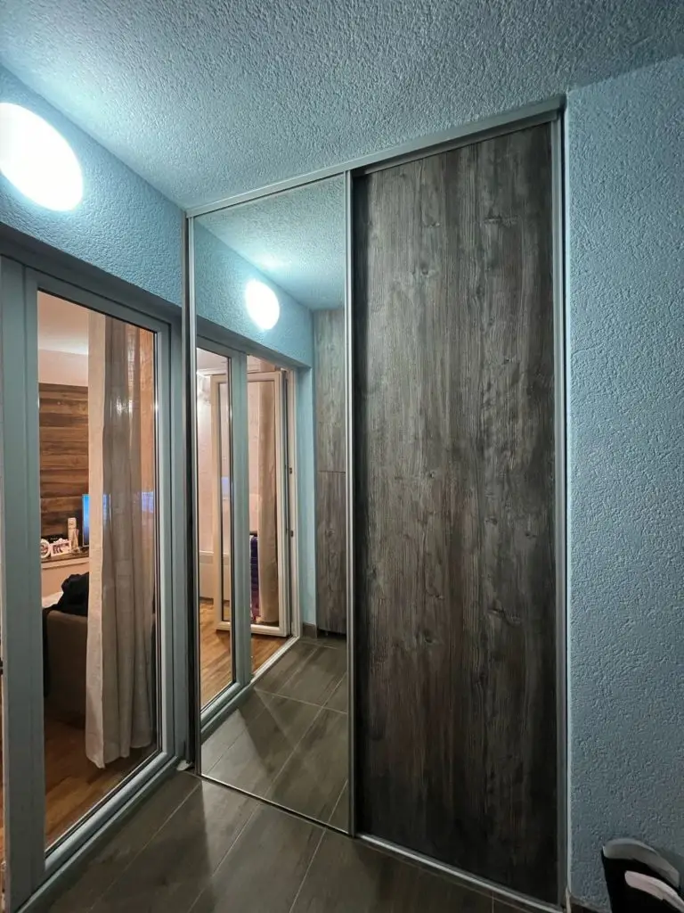 Narrow hallway with mirrored sliding closet doors and wood panels