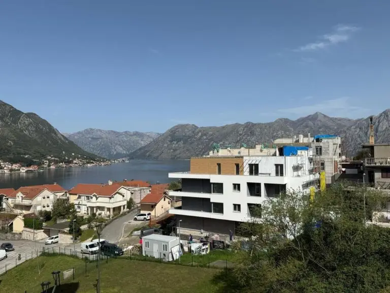 Modern building under construction overlooking bay and mountains
