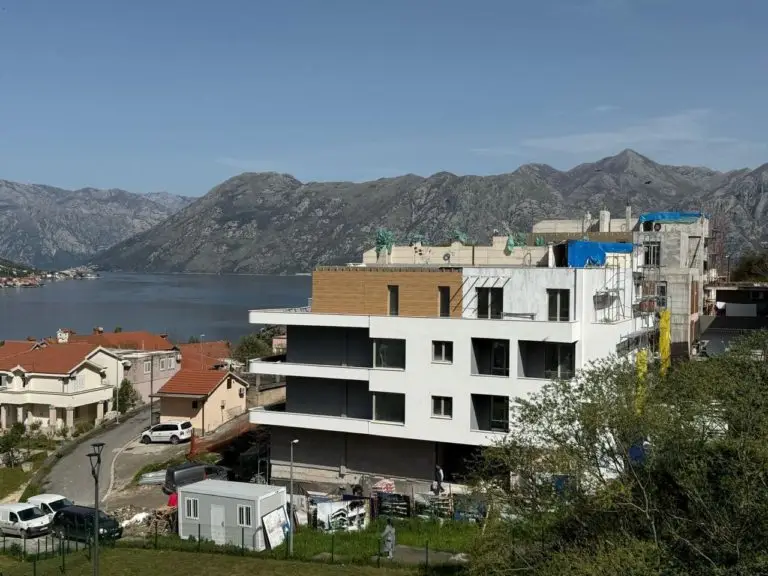 Partially constructed white apartment building by the bay and mountains