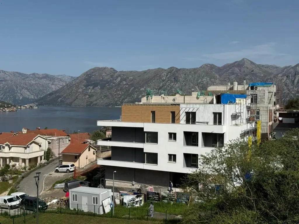 Modern apartment building under construction by the bay and mountains
