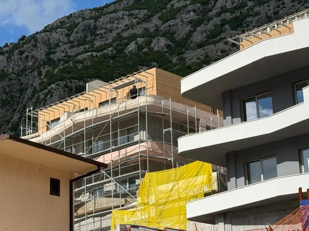 Modern apartment building under construction beside rocky mountain