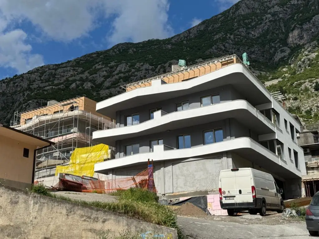 Modern apartment building under construction with mountain backdrop