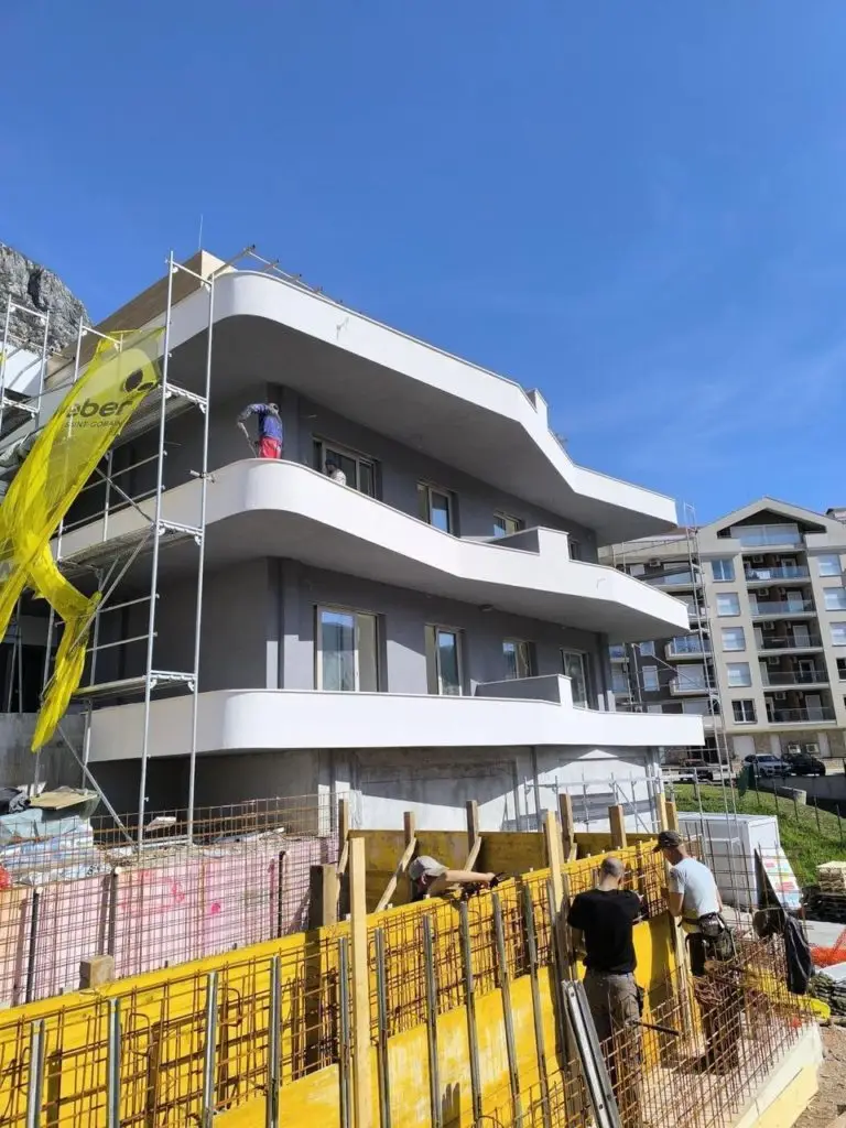 Modern apartment building under construction with workers and scaffolding