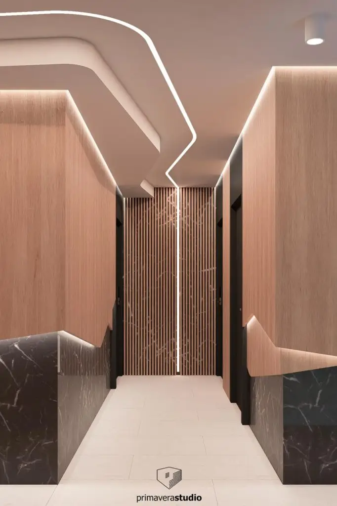 Modern corridor with wood panels, marble bases, and lit ceiling; primaverastudio logo