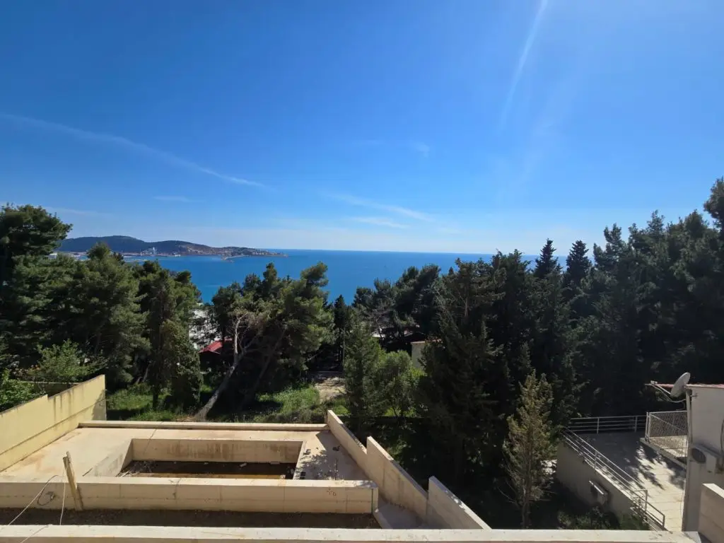 Sea view over trees and rooftop terrace wall