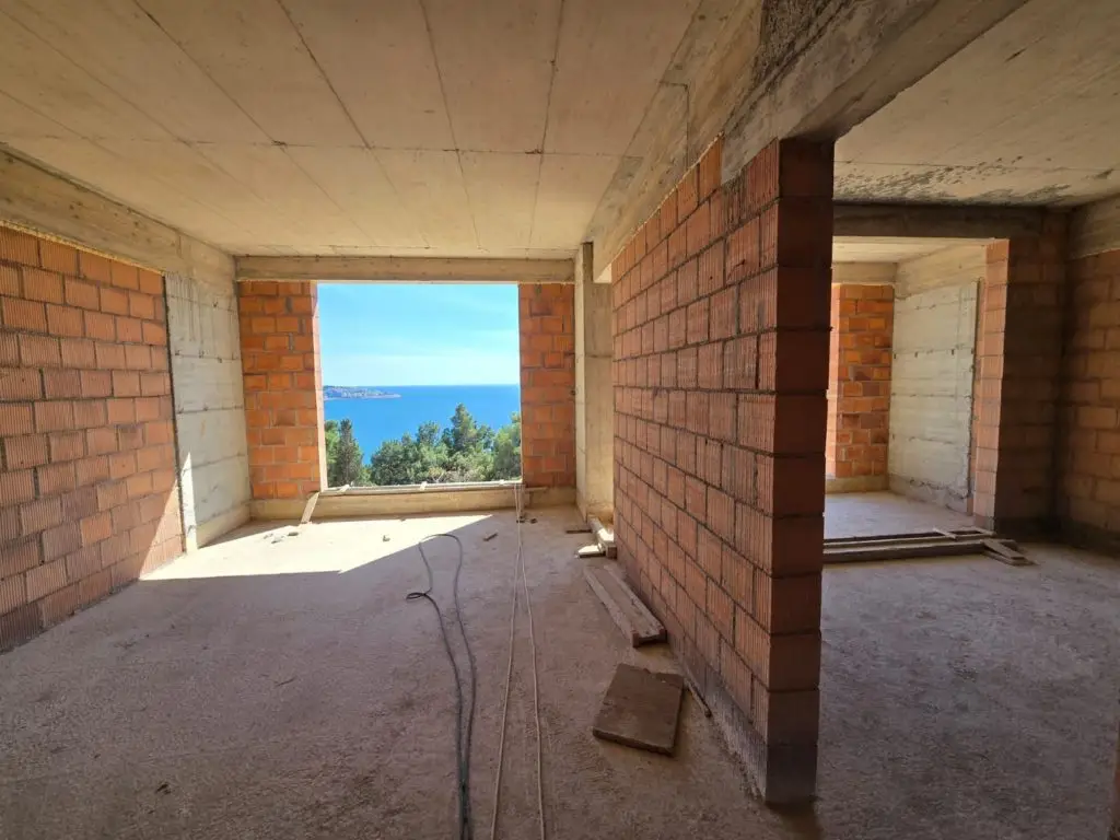 Unfinished apartment interior with brick walls and sea view