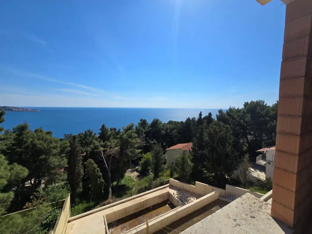 Sea view over pine trees and nearby buildings from balcony