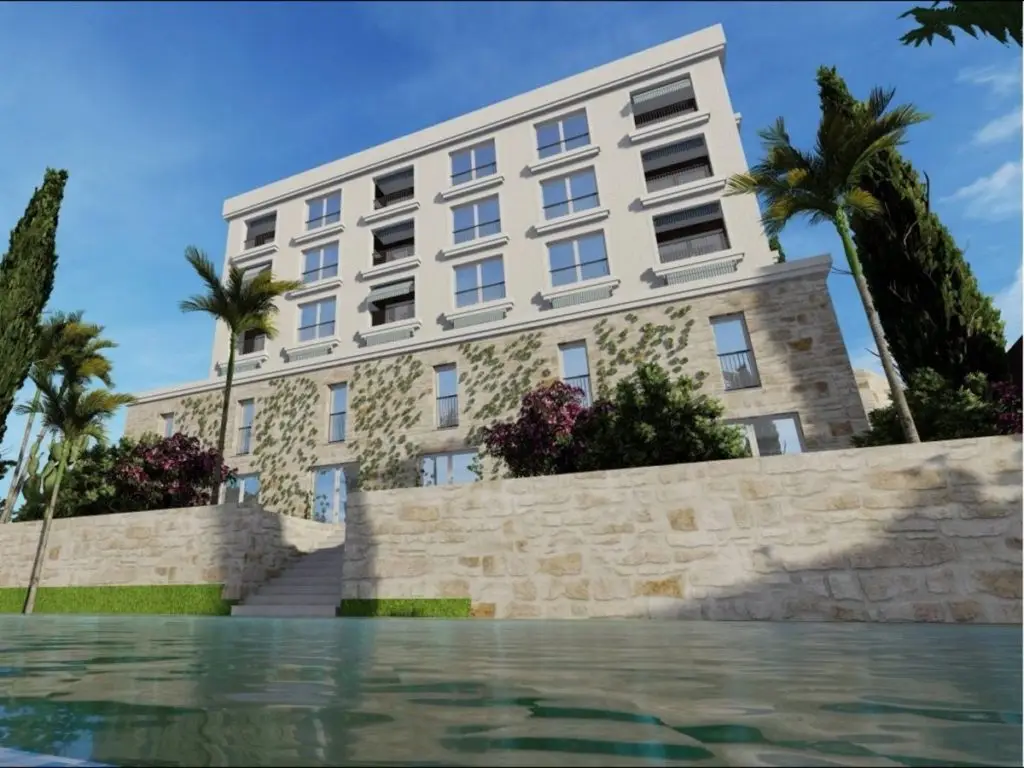 Modern apartment building with stone facade, palm trees, and pool
