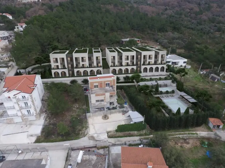 Aerial view of modern apartment complex with pool and hillside