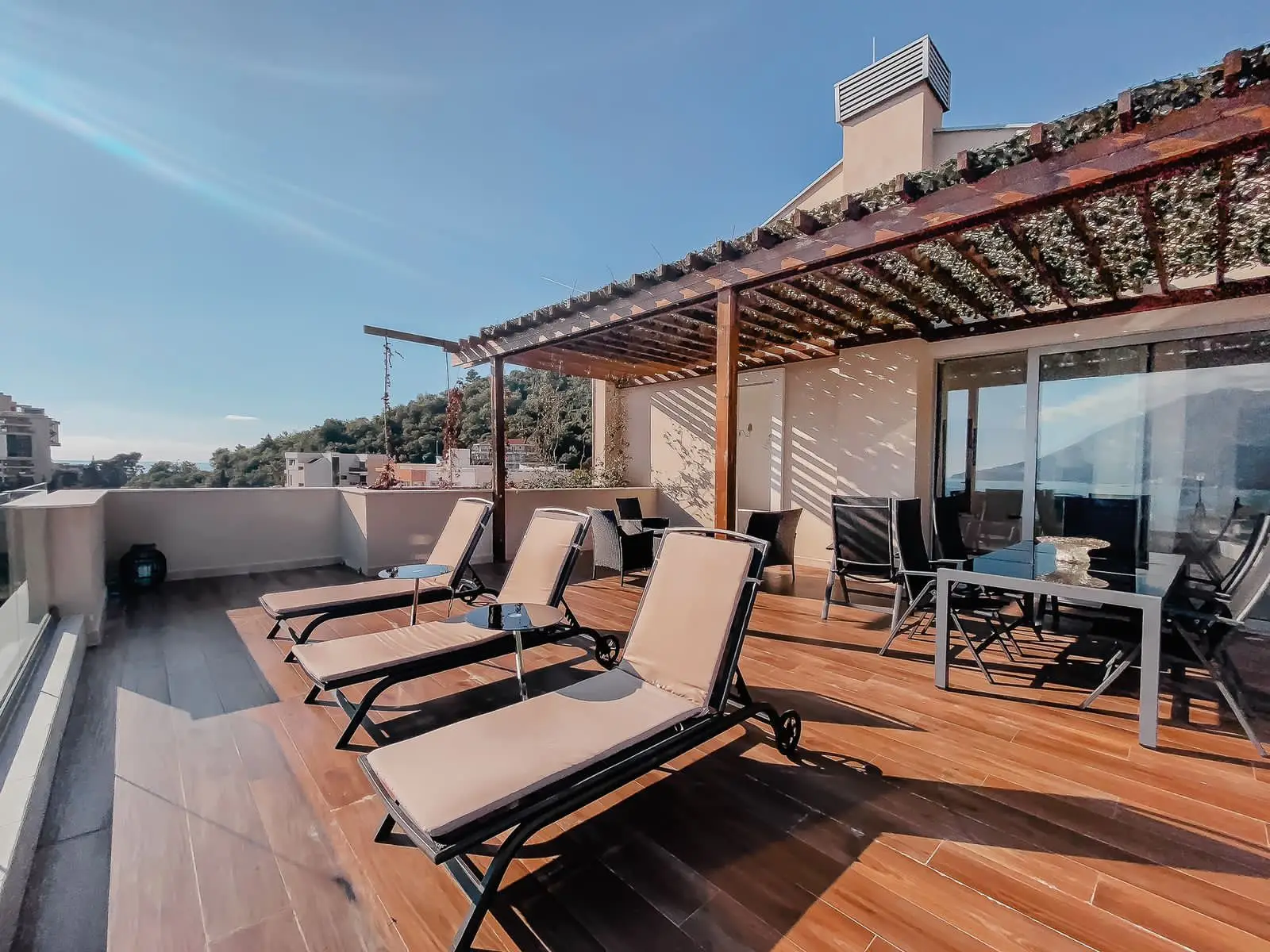 Rooftop terrace with lounge chairs, pergola, and sea view