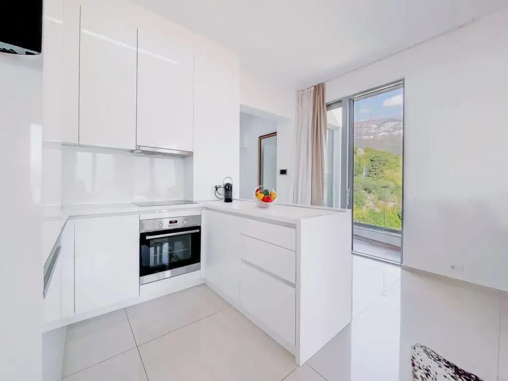 Modern white kitchen with built-in oven and balcony view