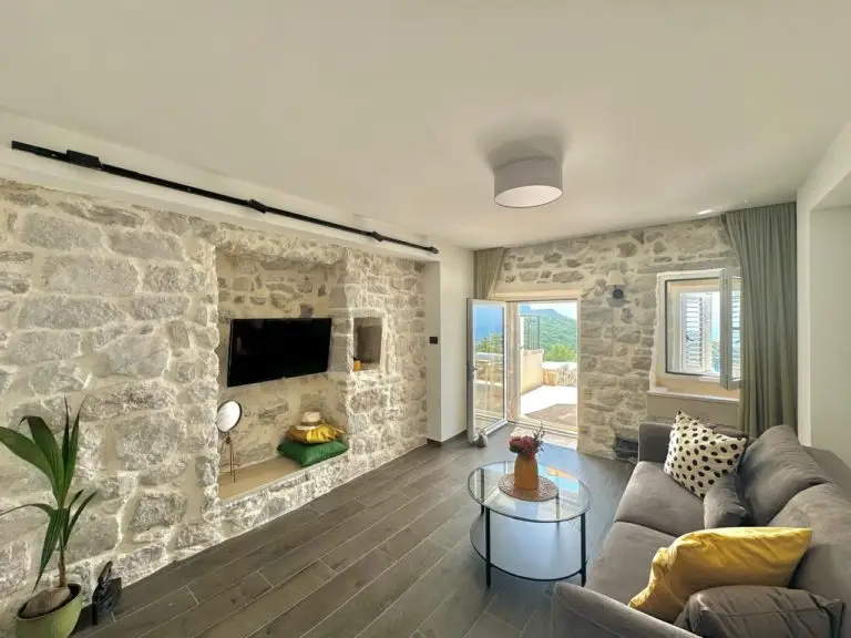 Stone-walled living room with sofa, TV, and open door