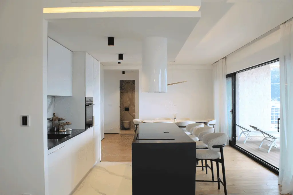 Modern white kitchen and dining area with black island and terrace doors