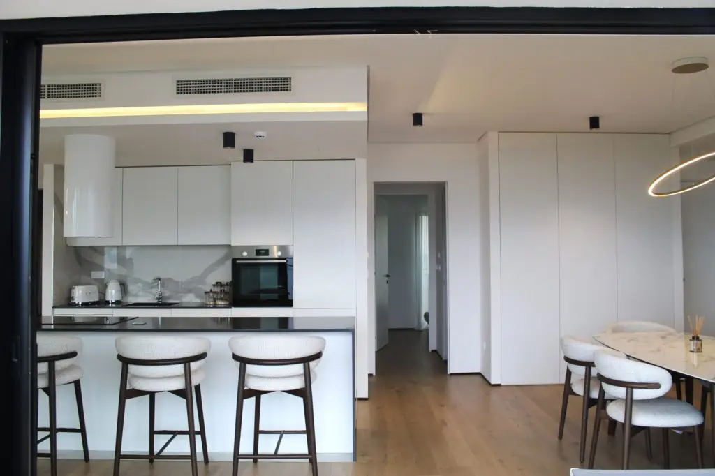 Modern white kitchen with island stools and dining table