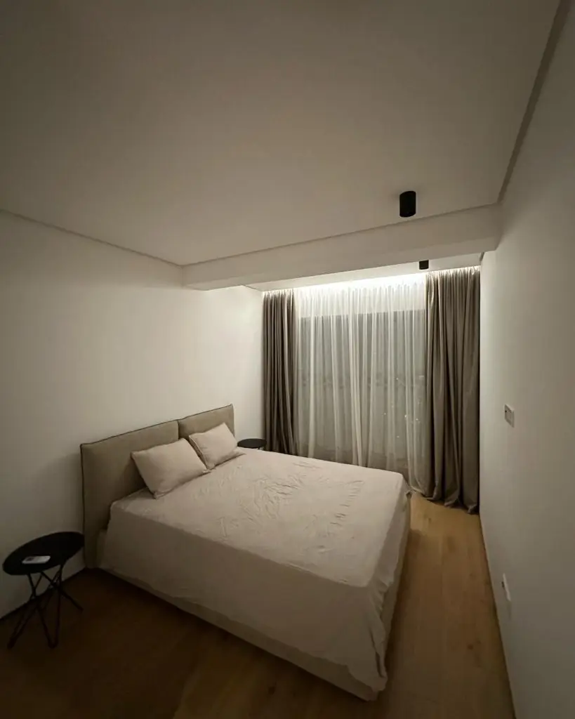 Minimalist bedroom with bed, curtains, and wood floor