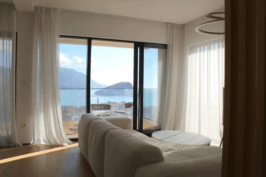 Bright living room with white sofa and sea view through balcony doors