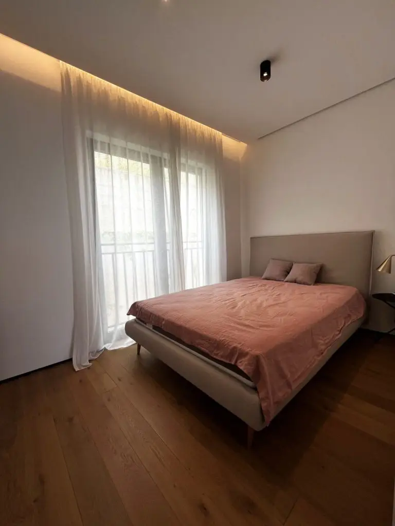 Modern bedroom with pink bedspread and sheer curtains