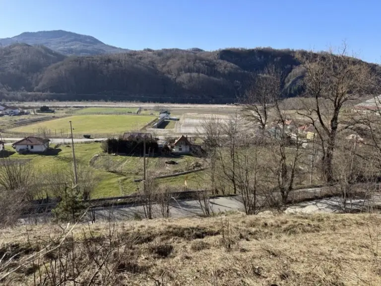 Rural valley with fields, houses, road, and mountains
