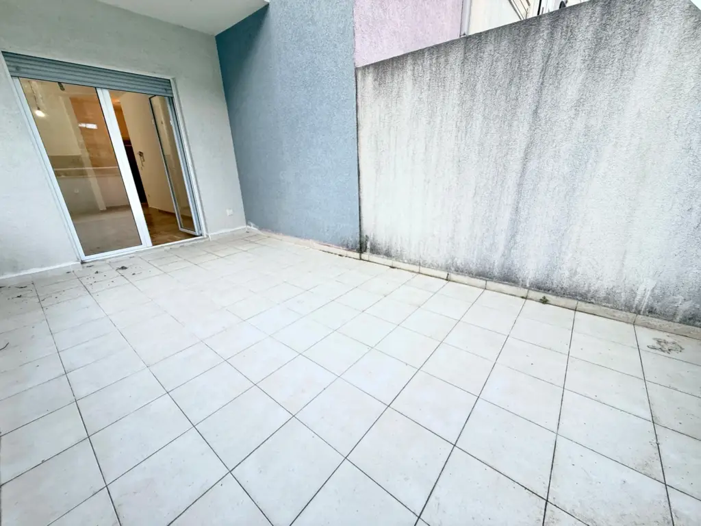 Empty tiled patio with sliding glass door and stained wall