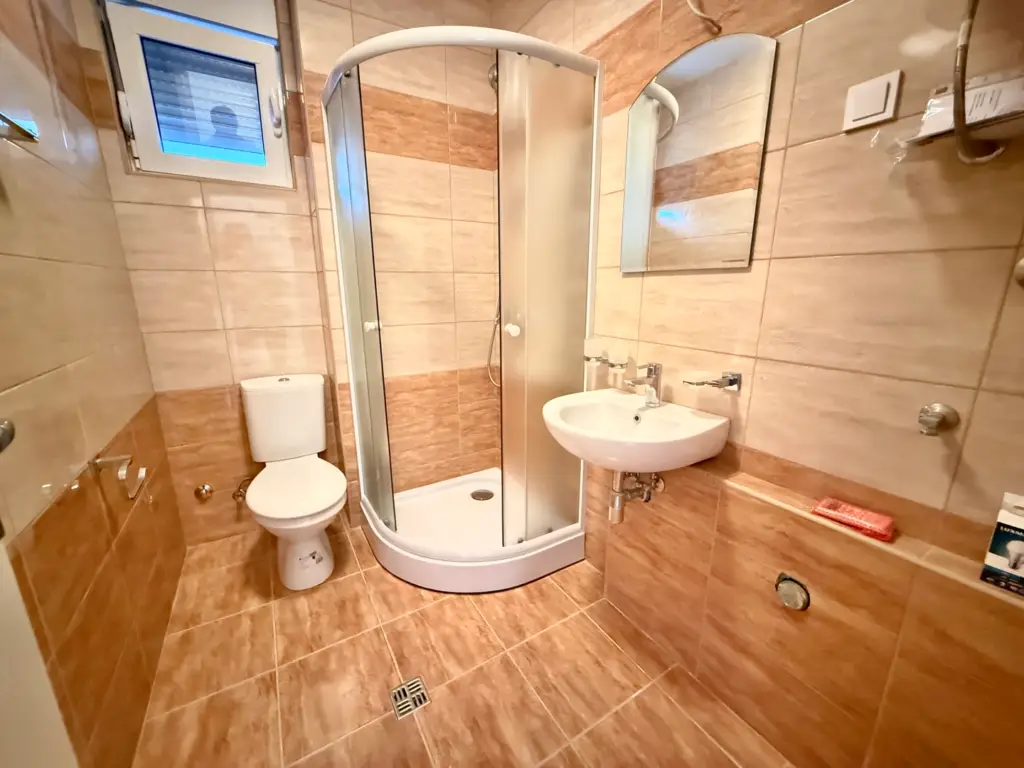 Bathroom with shower stall, toilet, and wall-mounted sink