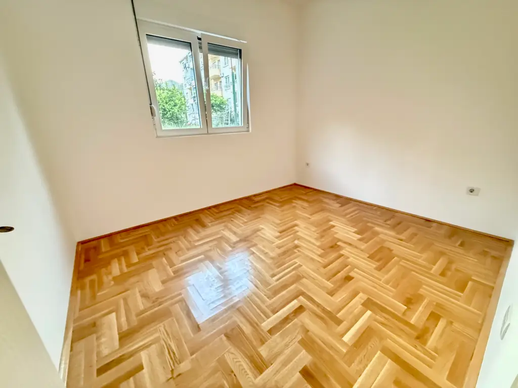 Empty room with herringbone wood floor and a window