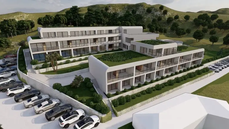Modern white apartment complex on a hillside with parking lot