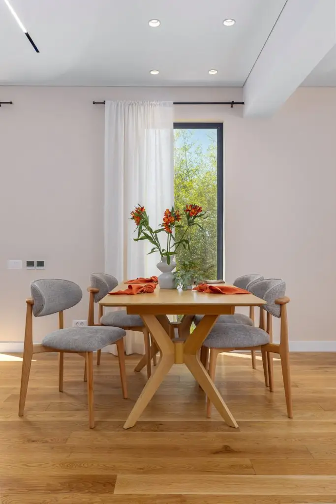 Dining table with four gray chairs and orange flowers