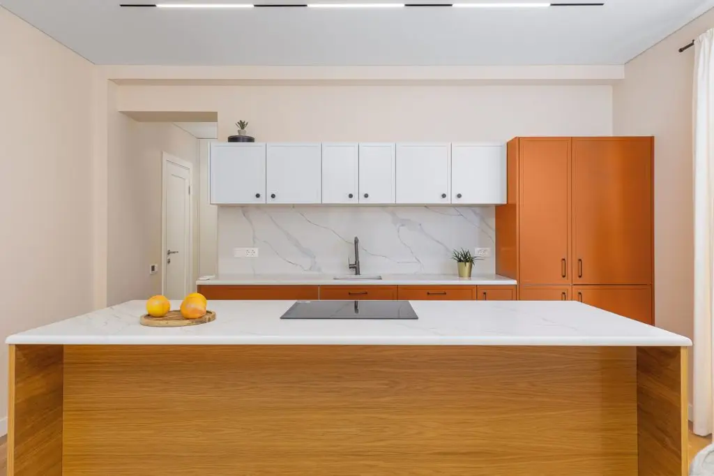 Modern kitchen with island, orange cabinets, and white upper cabinets