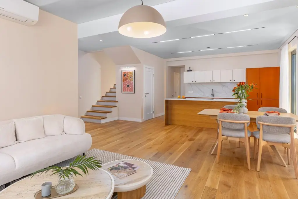 Open-plan living room with kitchen, staircase, and sofa