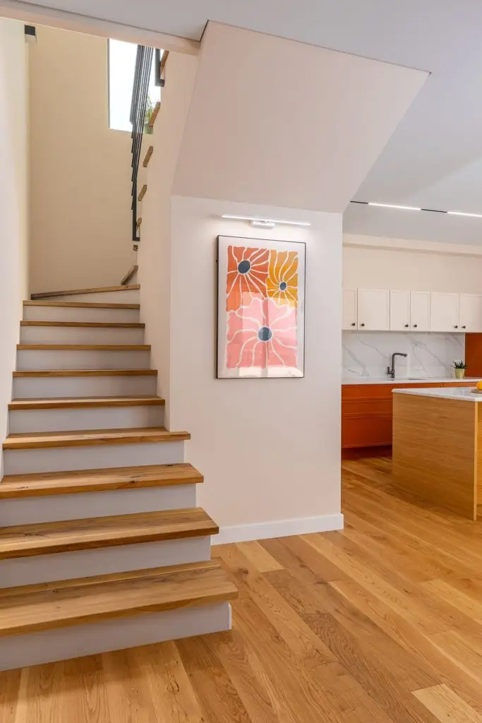 Wooden staircase beside kitchen and framed floral print