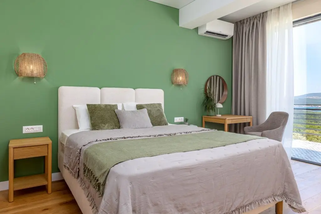 Bedroom with green wall, double bed, and balcony view