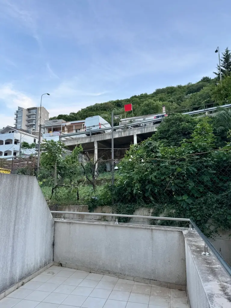 Tiled balcony overlooking hillside road and buildings