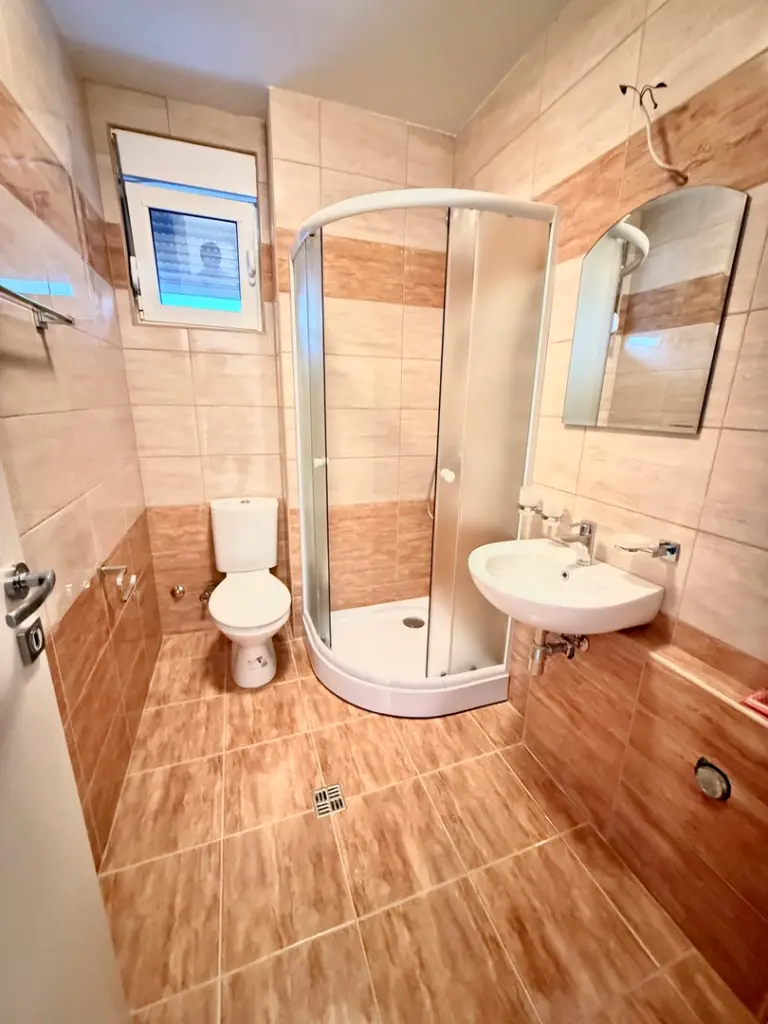 Small bathroom with shower, toilet, sink, and mirror