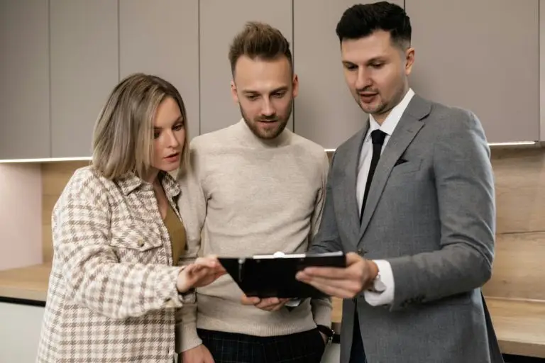 Three people reviewing a clipboard in a modern kitchen