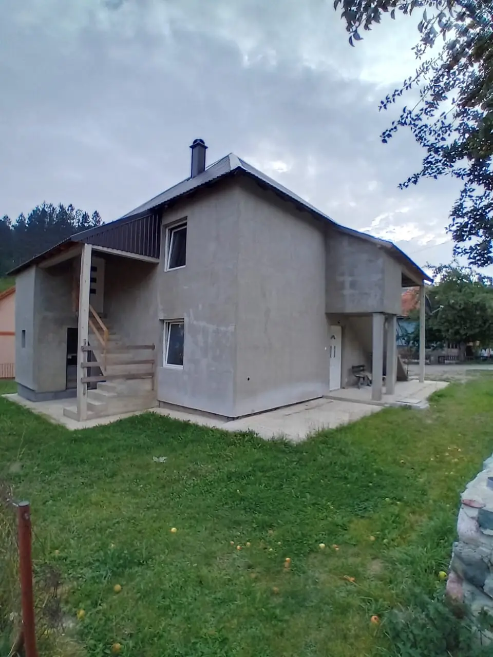 Gray unfinished house with metal roof and grassy yard