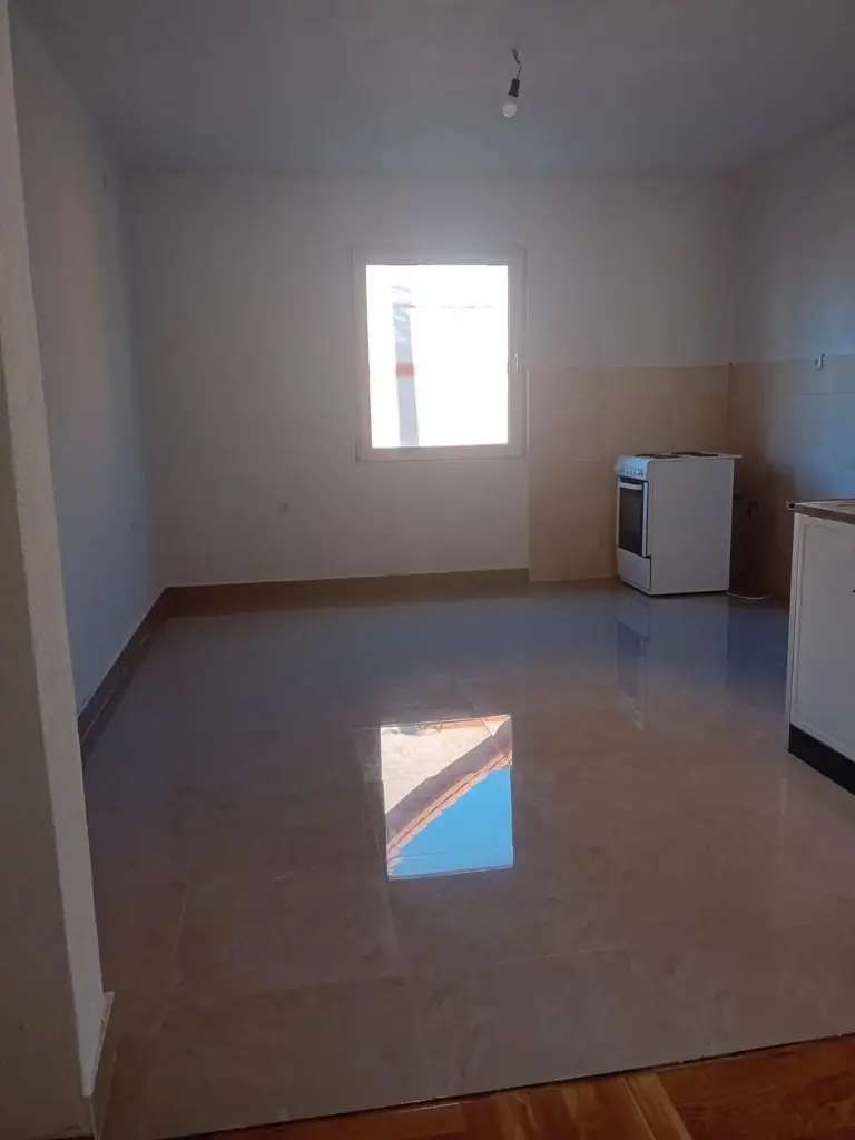 Empty kitchen with tiled floor, window, and stove