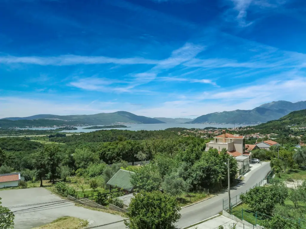 Bay and mountains above green hillside village with houses and road